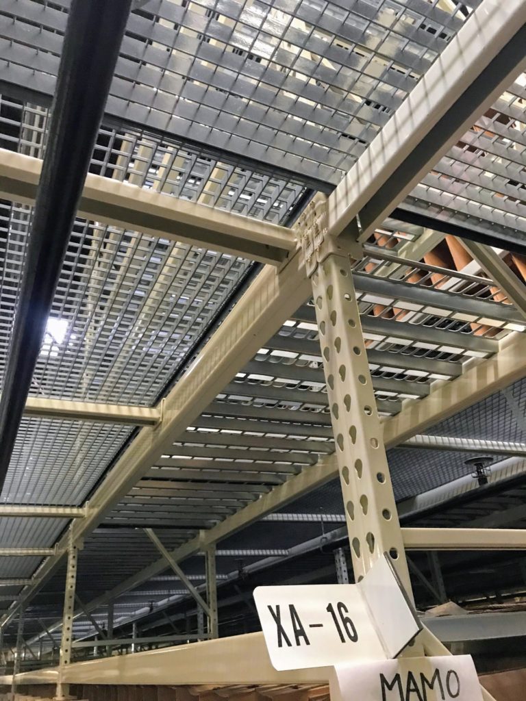 Pallet rack mezzanine with mezzanine bar grating and punch decking